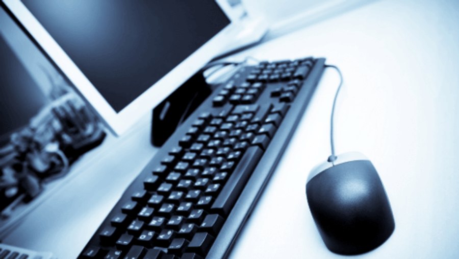 Workstation with a monitor, keyboard and mouse in a blue-lit office
