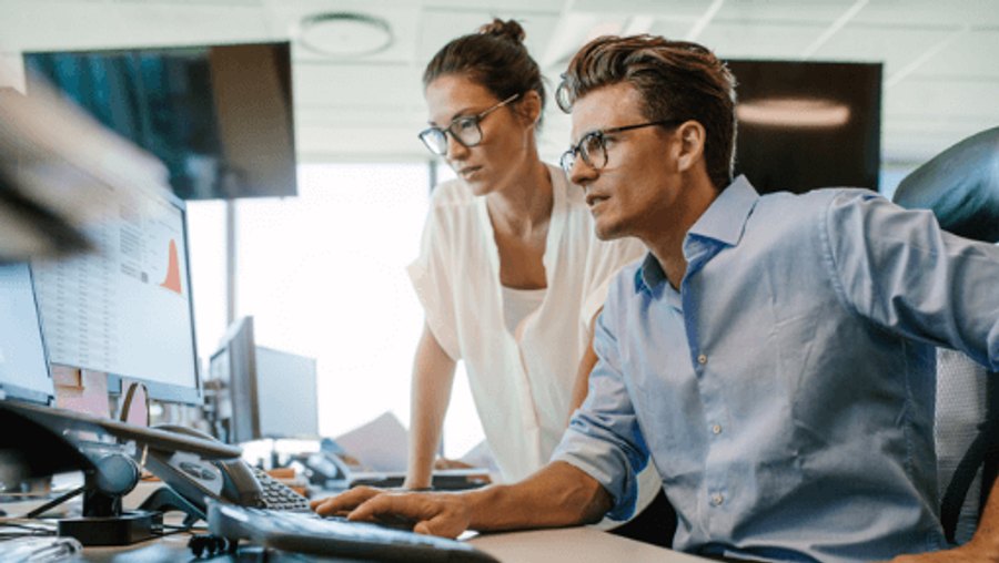 Two engineers reviewing monitoring dashboards on office monitors